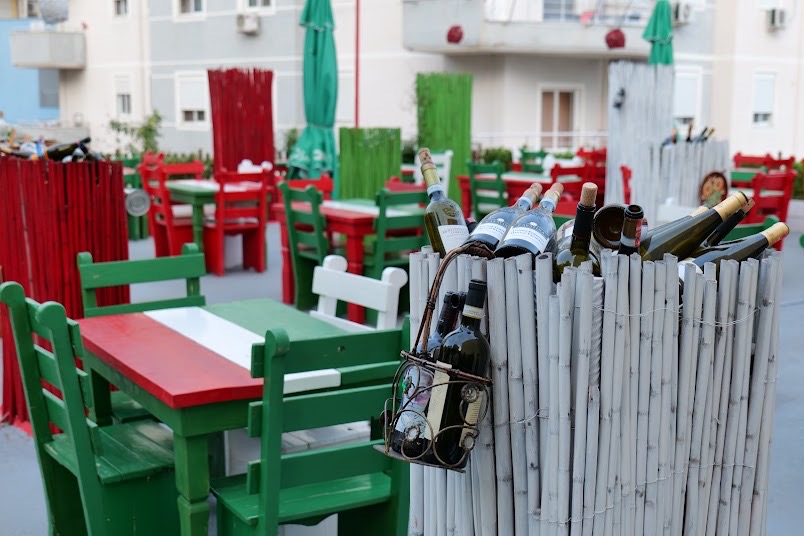The Maria Madalena terrace with green and red chairs and wine bottles