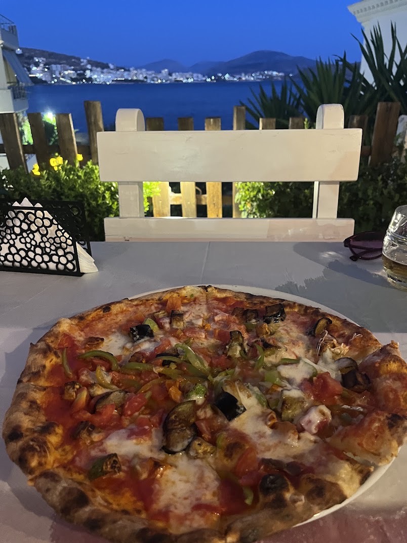 Wood-fired pizza with a Saranda bay view at dusk
